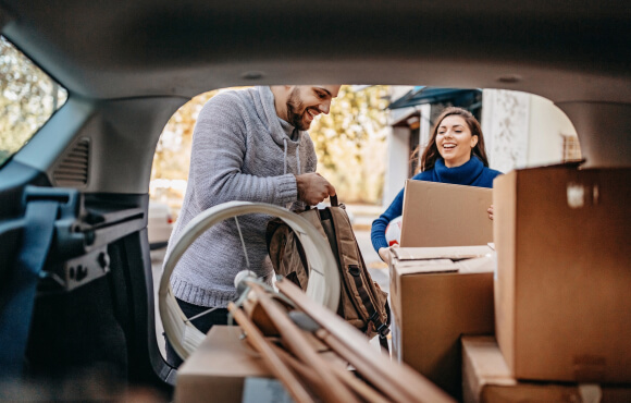 A young couple moving boxes out of an automobile.